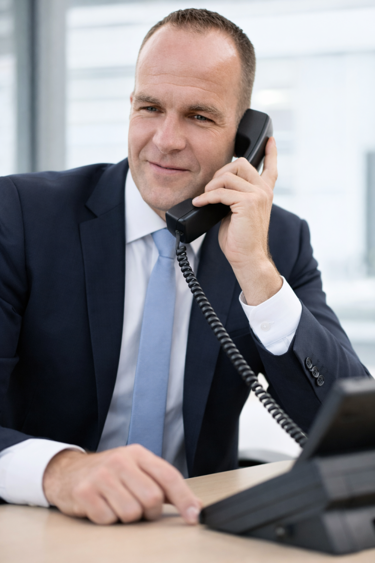 DJ Henne - Kontakt Geschäftsmann im Anzug, der am Telefon spricht, mit einem seriösen Lächeln.